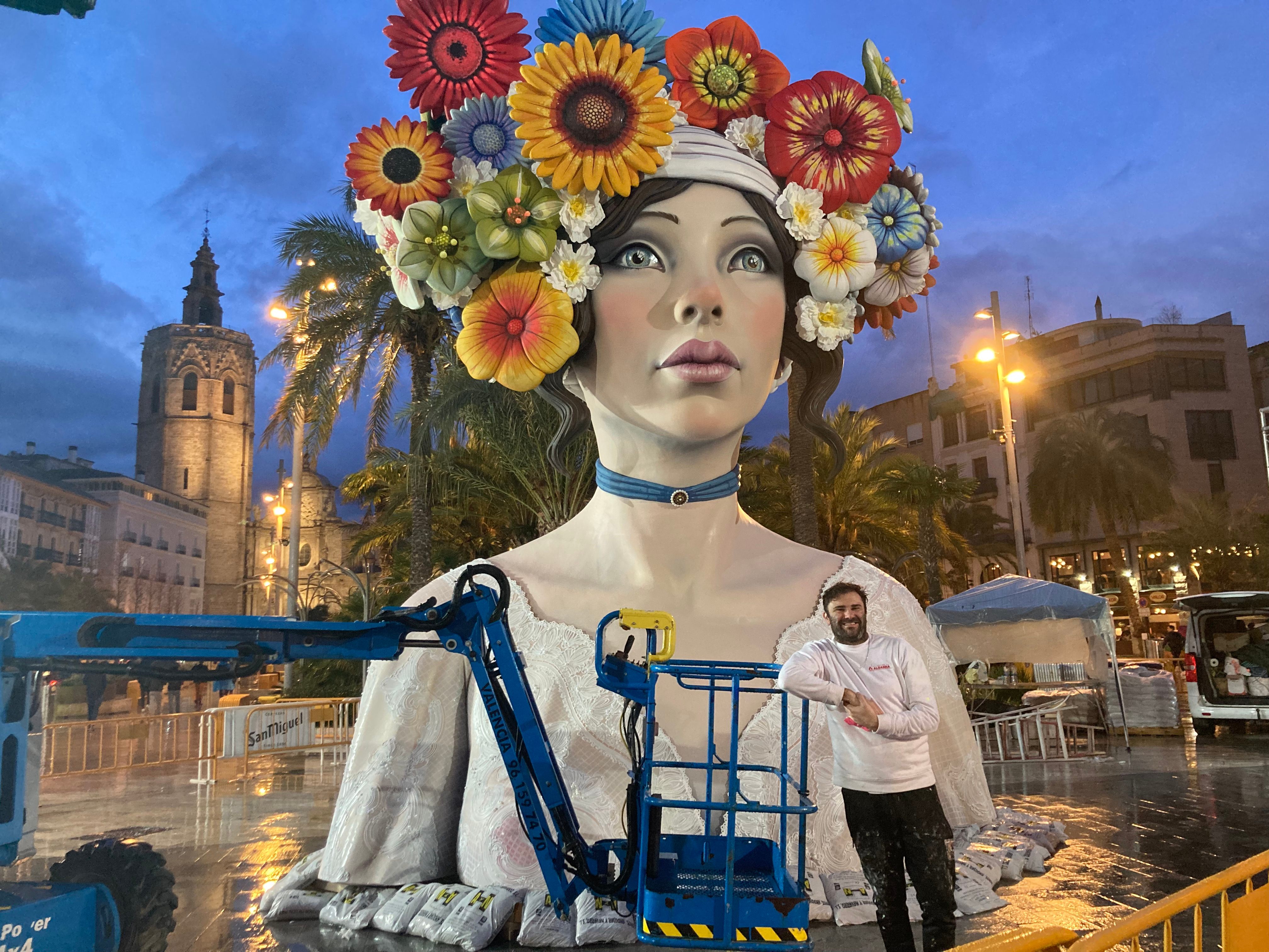 A falla artist poses with his work while installing it in the street.